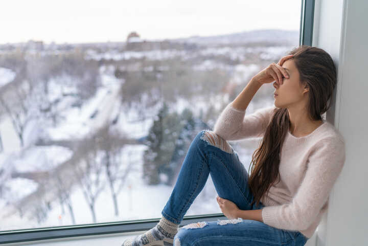 A woman suffering from SAD looking out of the window