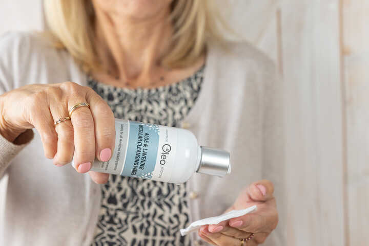 woman applying micellar cleansing water to a cotton pad