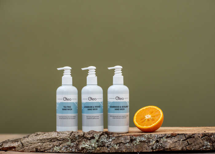 Oleo Bodycare Handwash Oleo Bodycare vegan hand wash placed on a wooden log slab with half an orange to showcase the natural ingredients used